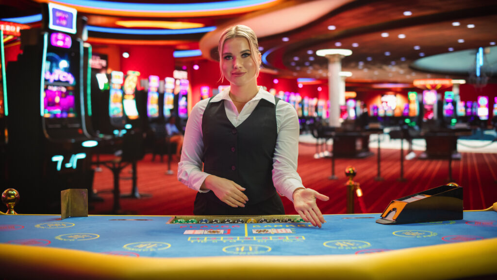 professional female croupier in casino dealing playing cards on a baccarat table. beautiful dealer of a live online casino reveals winning results of the card game bets, looking at the camera