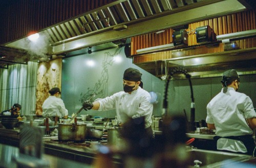 Koks in witte koksbuizen aan het werk in een restaurantkeuken